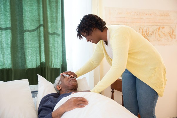 Woman nurturing older gentleman with hand on his forehead and one on his heart